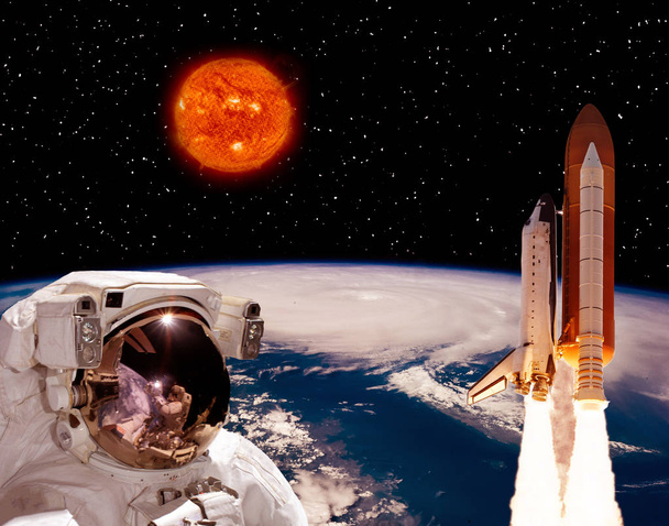 Astronauta a olhar para o foguetão que voa da Terra. Grande sol
  - Foto, Imagem