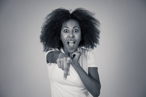Beautiful shocked african american woman looking and pointing at something unbelievable or having great success with surprised and happy face and gestures. In People and human emotions and expressions. - Photo, image