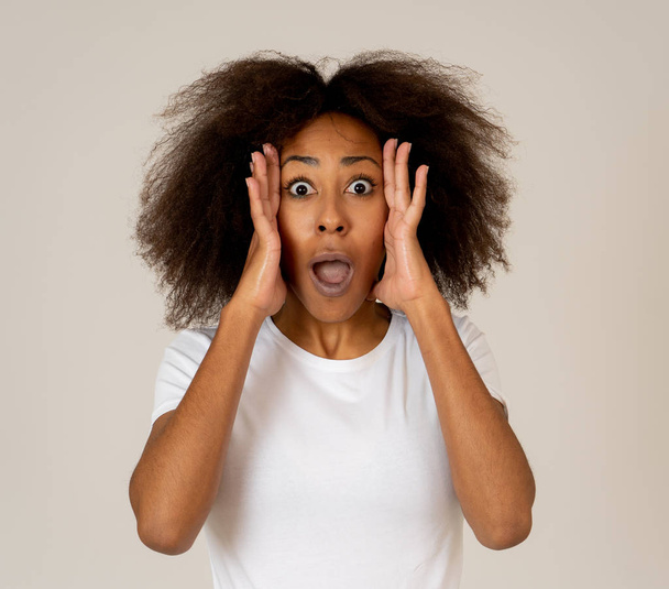 Beautiful shocked african american woman looking and pointing at something unbelievable or having great success with surprised and happy face and gestures. In People and human emotions and expressions. - Foto, Imagen