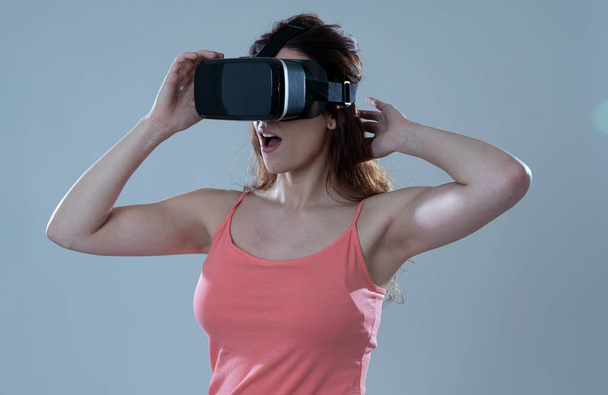 Curious woman happy and excited to use virtual reality goggles feeling excited about simulation, exploring virtual life making happy gestures. In New technology Virtual Augmented Reality concept. - Foto, imagen