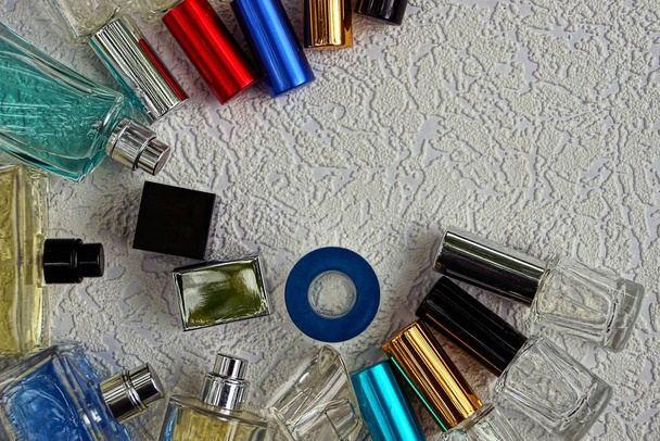 Värilliset lasipullot, joissa hajuvettä harmaalla pöydällä
 - Valokuva, kuva