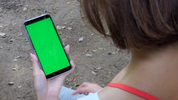 Азіатські жінки, використовуючи смартфон для Інтернету та електронної пошти в міському парку. Щасливий японський леді Холдинг стільниковий телефон. Людей і технологій. Зелений екран і порожній монітор для веб-сайту - Кадри, відео