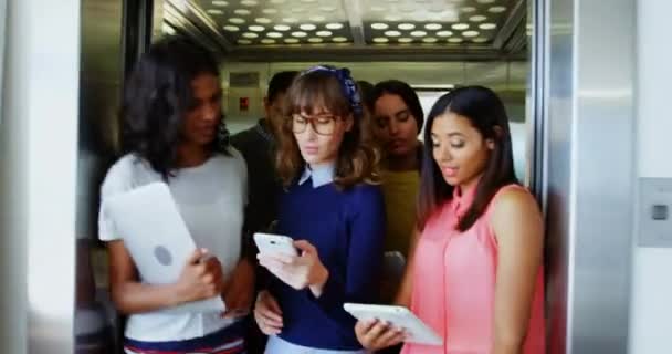 Animation of emoji icons flying up with a group of multi-ethnic students leaving a classroom and holding smartphones and tablets in the background 4k - Felvétel, videó