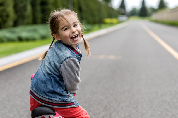 Szczęśliwa dziewczyna na małym rowerze. - Zdjęcie, obraz