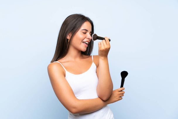 Young girl holding makeup brush over isolated background - Foto, Bild