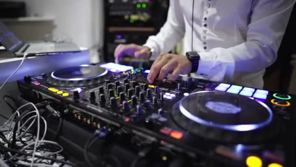 DJ op de console in een nachtclub-close-up op de console en op de handen van de DJ die naar het ritme van de muziek beweegt - Video
