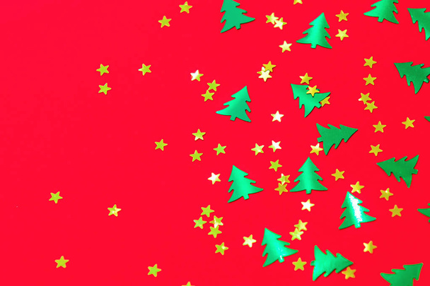 green christmas trees and gold stars confetti sparse on red back - Photo, Image