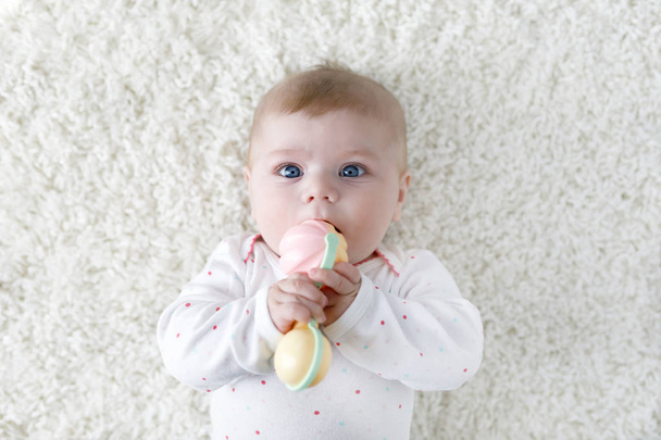 Cute baby girl playing with colorful pastel vintage rattle toy - Photo, Image