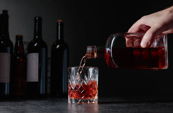 Бармен наливает виски в стакан в баре. - Фото, изображение