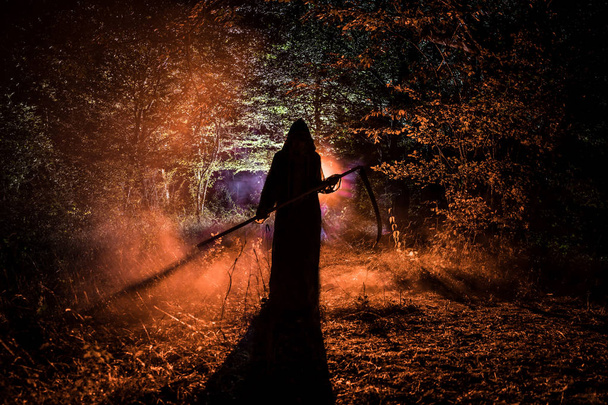 Muerte con una guadaña en el oscuro bosque brumoso. Mujer horror fantasma
 - Foto, imagen