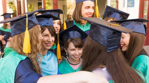 Een groep jonge vrouwelijke afgestudeerden. Vrouwelijke Graduate is glimlachend AG - Foto, afbeelding
