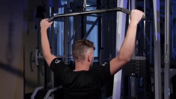 Lat pulldown.A young man does a back muscle exercise on a simulator.copy space - Filmati, video