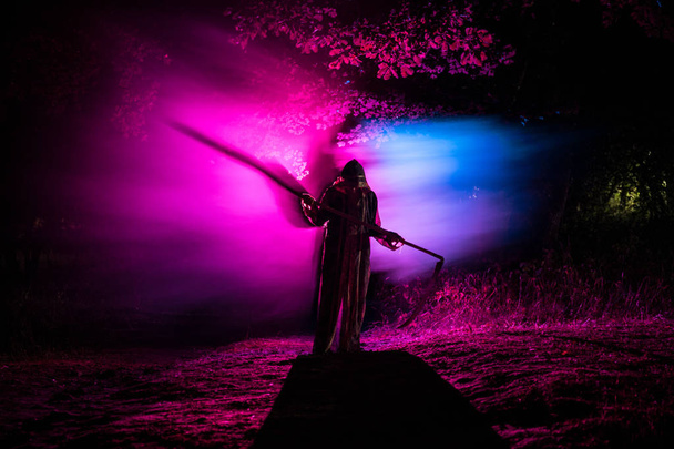 Смерть с косой в темном туманном лесу. Женщина-призрак ужасов держит жнеца в лесу
 - Фото, изображение