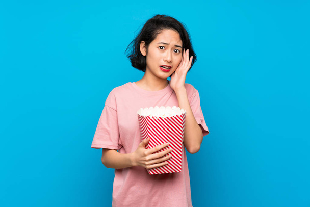 Asiatique jeune femme manger popcorns avec surprise et choqué expression faciale
 - Photo, image