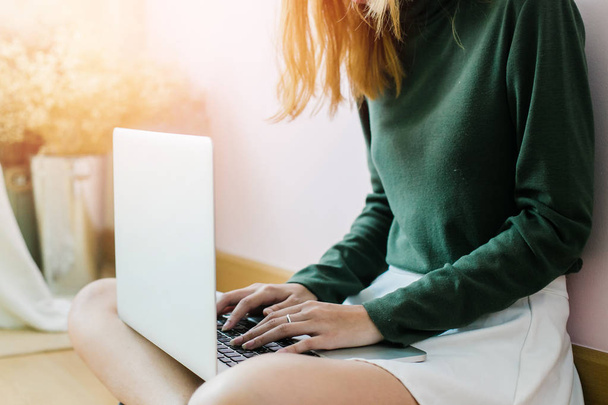 Счастливая случайная красивая женщина работает на ноутбуке, сидя в
  - Фото, изображение