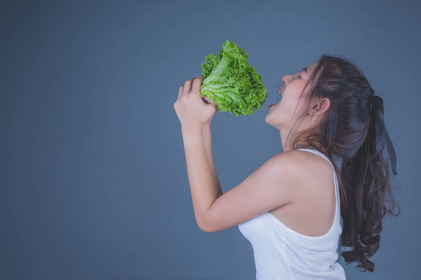 Chica sostiene las verduras sobre un fondo gris. - Foto, Imagen