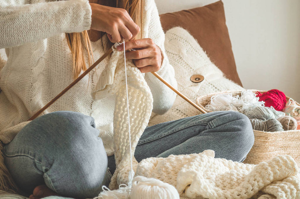 Beautiful girl knits a warm sweater on the bed. Accessories for knitting. - Foto, imagen