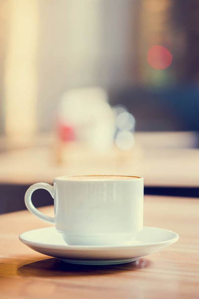 Latte Coffee in einer Tasse auf Holztisch und Café verschwimmen Backg - Foto, Bild