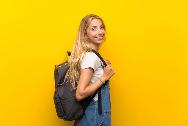 Blonde jeune femme sur fond jaune isolé avec sac à dos
 - Photo, image