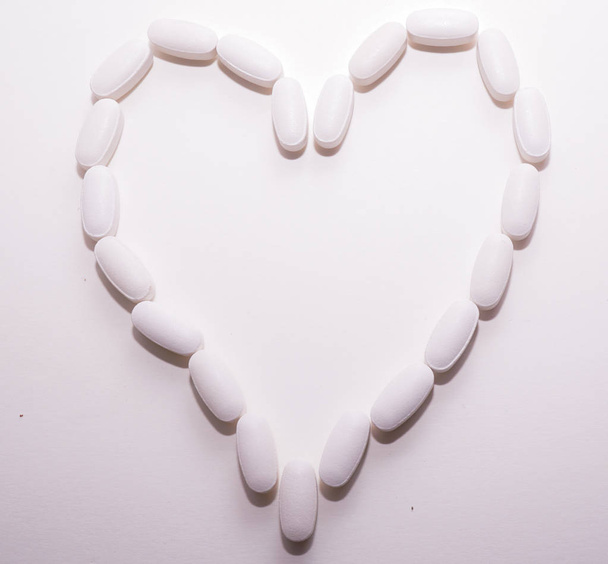 White oval heart shaped pills closse to each other as a background for pharmacy concept. - Valokuva, kuva