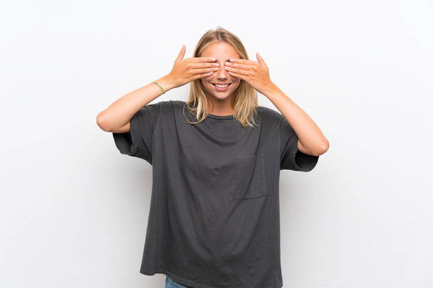 Blonde young woman over isolated white background covering eyes by hands - Foto, Bild