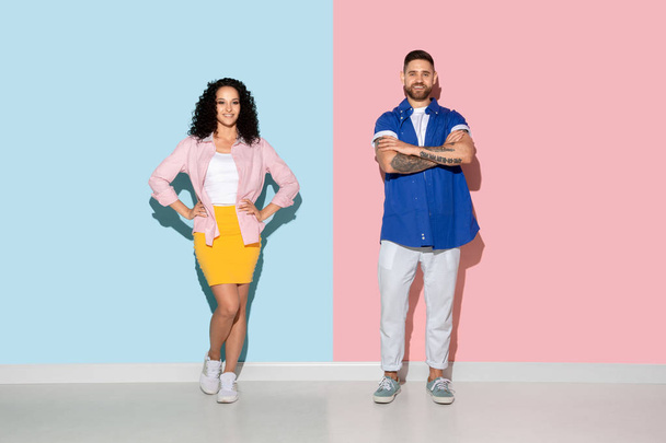 Fiatal érzelmi férfi és nő rózsaszín és kék háttér - Fotó, kép