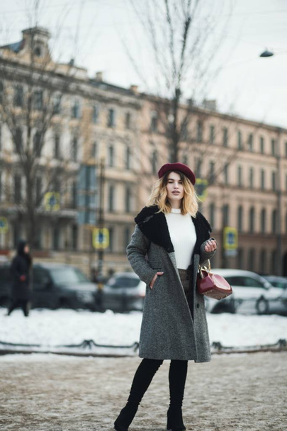 Messa a fuoco superficiale colpo verticale di una donna bionda attraente in abiti invernali in posa per strada - Foto, immagini