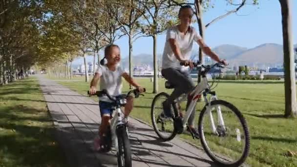 Mãe e filha está montando uma bicicleta ao longo da beira-mar juntos, steadicam tiro
 - Filmagem, Vídeo