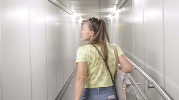 Widok z tyłu młodej kobiety spaceru na przejściu na samolot - Materiał filmowy, wideo