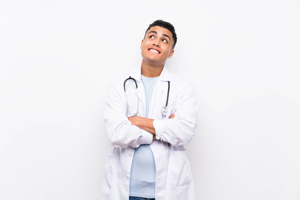 Young doctor man over isolated white wall looking up while smiling - Фото, изображение