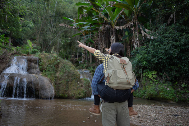 I giovani viaggiatori si tengono per mano, camminando felici nella cascata
. - Foto, immagini