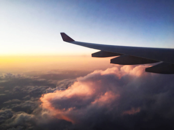 Aile d'avion par la fenêtre d'un illuminateur. Voler haut au-dessus des nuages. Gros plan
. - Photo, image