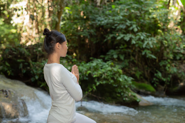 Beautiful girls are playing yoga at the park. Among the natural waterfalls in the forest, exercise concepts - 写真・画像
