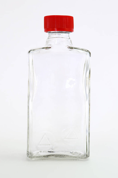 Γυάλινο μπουκάλι κόκκινο καπάκι ενιαίο κενό απομονωμένη λευκό φόντο φρεσκάδα βότκα καθαρό νερό στούντιο ορυκτή καθαρότητα μπροστινή όψη κρυστάλλινο φαγητό - Φωτογραφία, εικόνα
