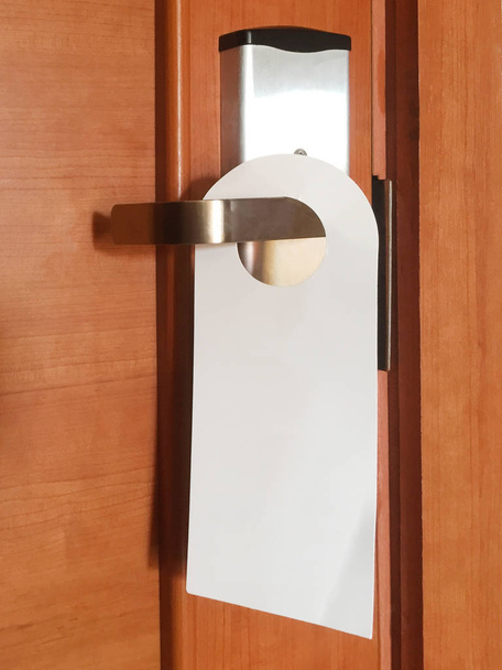 Dorhenger on the doorknob. A lock with a metal handle and a card reader on a wooden door. Close-up. There is a place for text - Photo, Image