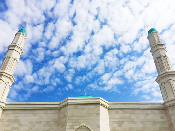 高いミンナレット、モスクのドームと壁の一部は、白い雲と美しい青い空に対して光の石で飾られました。テキストの場所があります. - 写真・画像