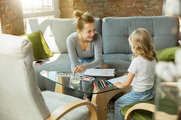 Teacher and little girl, or mom and daughter. Homeschooling concept - Valokuva, kuva