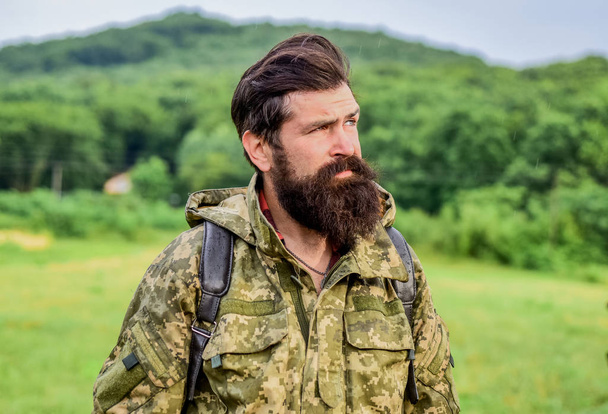 Brutal manly guy. Hike and travel. Weekend leisure and vacation. Hiker bearded man hiking. Hiker ready for adventures. Man bearded backpacker wear camouflage jacket nature background. Hiker tourist - Fotografie, Obrázek
