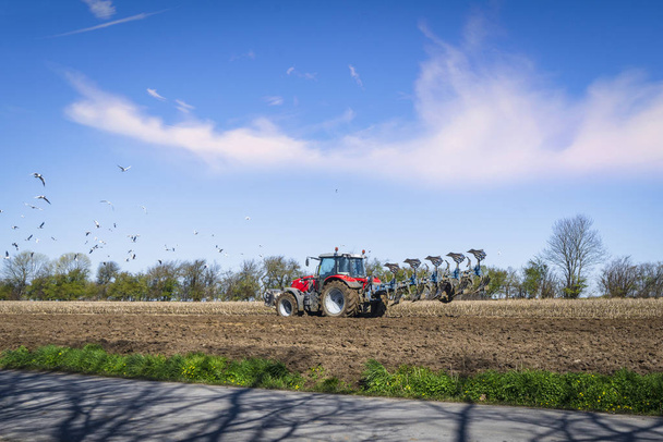 Vörös traktor szántás egy vidéki területen a tavaszi - Fotó, kép