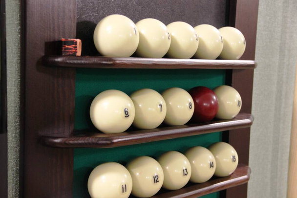 білі кульки і один коричневий бал на полиці-підставка для більярдних куль в ряд для гри в російський більярд. забавна гра і спорт - Фото, зображення