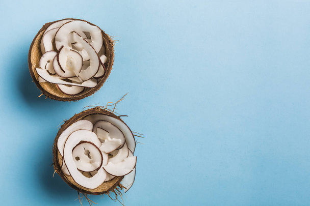 Patatas de coco en un tazón de coco sobre un fondo azul
 - Foto, Imagen