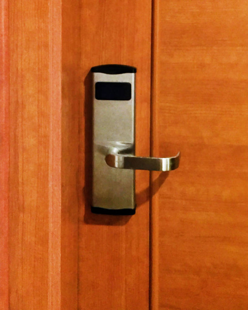 Uma fechadura com uma alça de metal e um leitor de cartões em uma porta de madeira. Close-up
. - Foto, Imagem