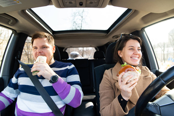 young couple eating fast food in car - Photo, Image