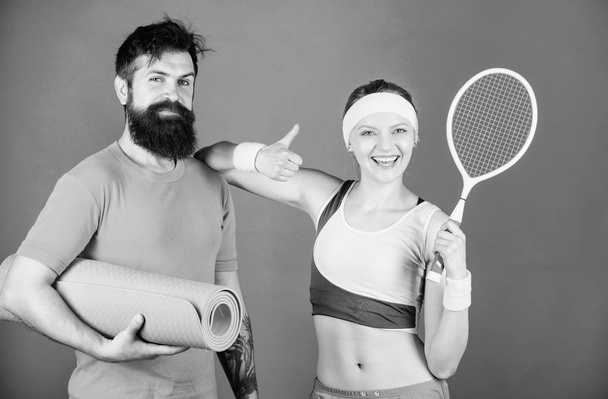 Get your Game on. Strong muscles and body. Sporty couple training with fitness mat and tennis racket. Athletic Success. Sport equipment. Happy woman and bearded man workout in gym - 写真・画像