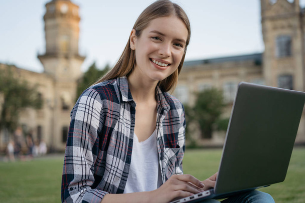 Happy student studying in park. Online education concept. Portrait of successful freelancer copywriter working project online. Beautiful smiling woman using laptop computer, typing on keyboard, searching information, planning working process  - Фото, зображення