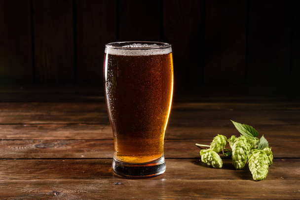 コピースペース付きの木製の背景にガラスビール。ラガービール付きフルグラス、クローズアップ - 写真・画像