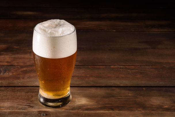 Bière en verre sur fond bois avec espace de copie. Plein verre avec bière blonde, gros plan
 - Photo, image