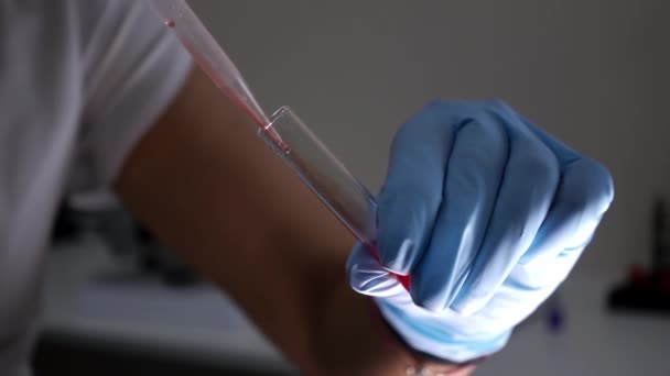 Hand eines Medizintechnikers in einem Einmalhandschuh hält ein Reagenzglas - Filmmaterial, Video