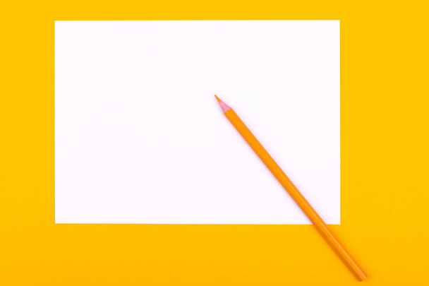 A fehér papírlapot a rajzok, szövegek és jegyzetek mellett egy ceruzát fekszik narancssárga háttér - Fotó, kép