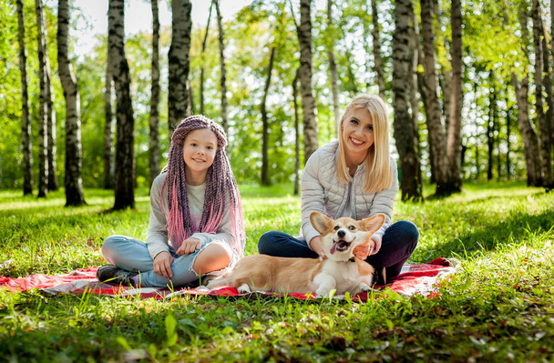 Una joven madre con un niño paseando con un perro en un parque de verano
 - Foto, imagen
